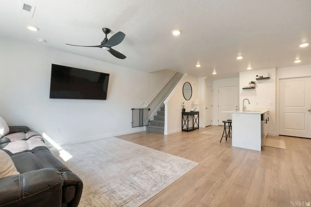Open-concept living area with wood-finish flooring, a modern ceiling fan, and recessed lighting