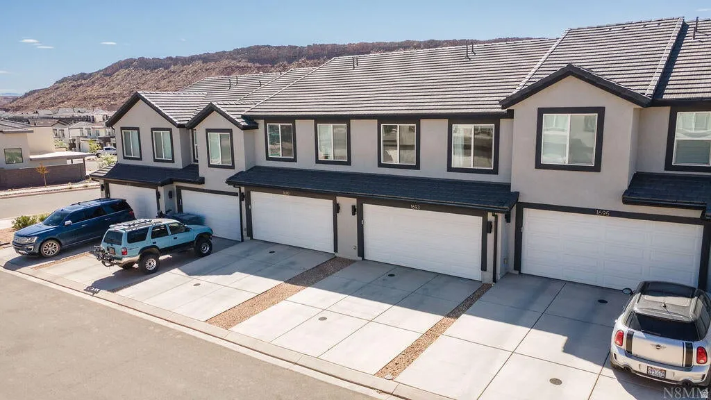 Multi-unit property featuring contemporary stucco exteriors with dark trim, individual garages, and concrete driveways