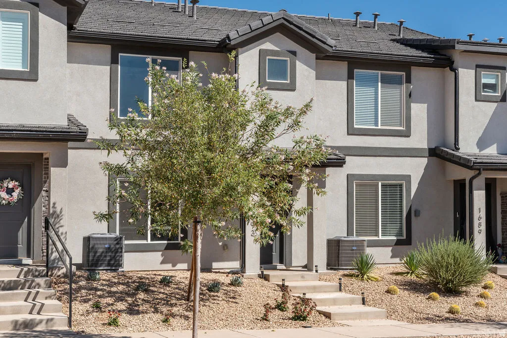 Contemporary townhome exterior featuring light gray stucco siding with dark gray trim accents