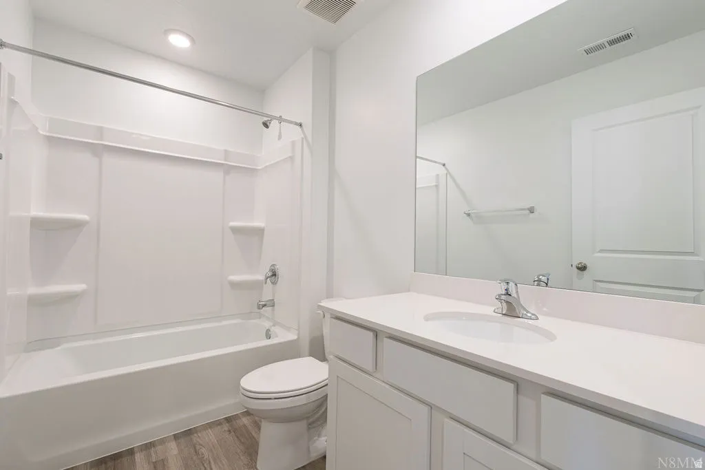 Bathroom featuring a white vanity with an integrated sink, polished chrome faucet, and a large mirror
