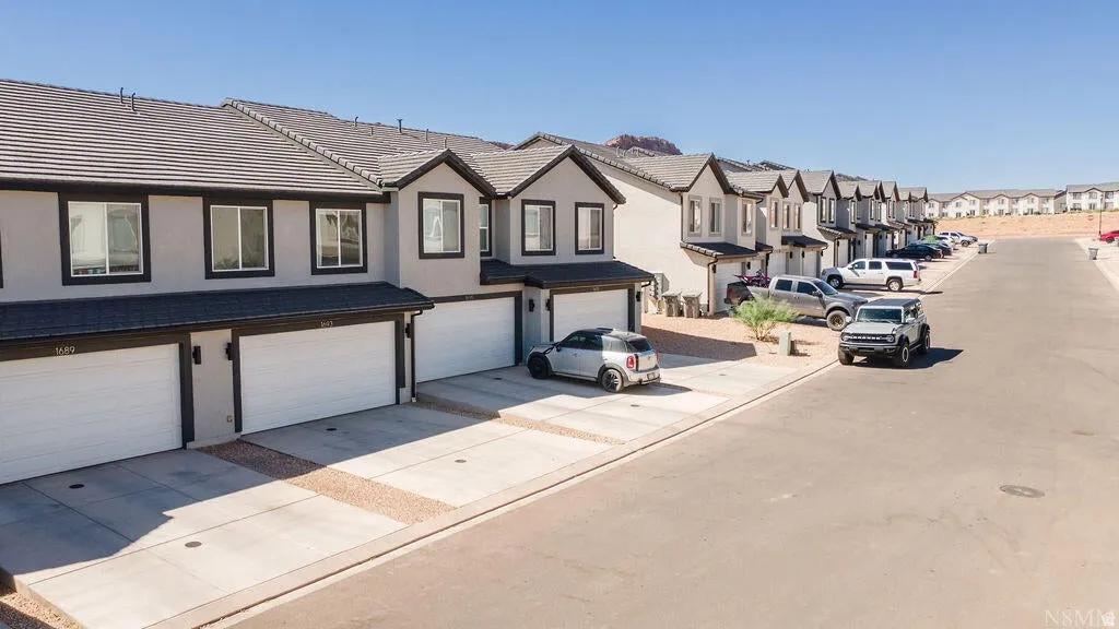 Contemporary townhome exteriors featuring light gray stucco, dark trim, and dark tile roofing