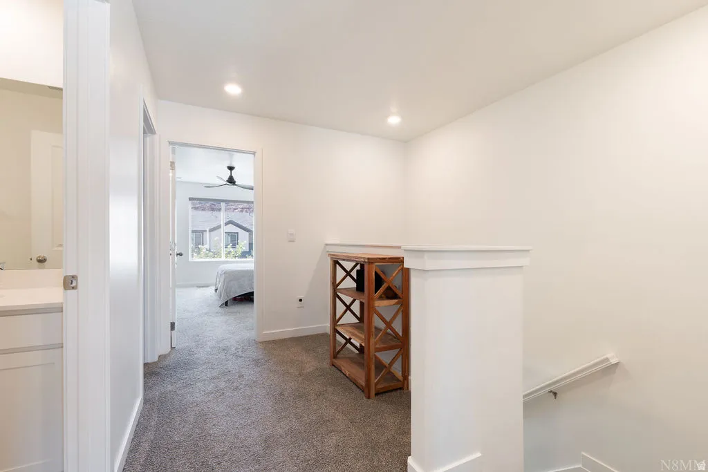 Upper-level hallway with plush gray carpeting, recessed lighting, white trim, and a white balustrade