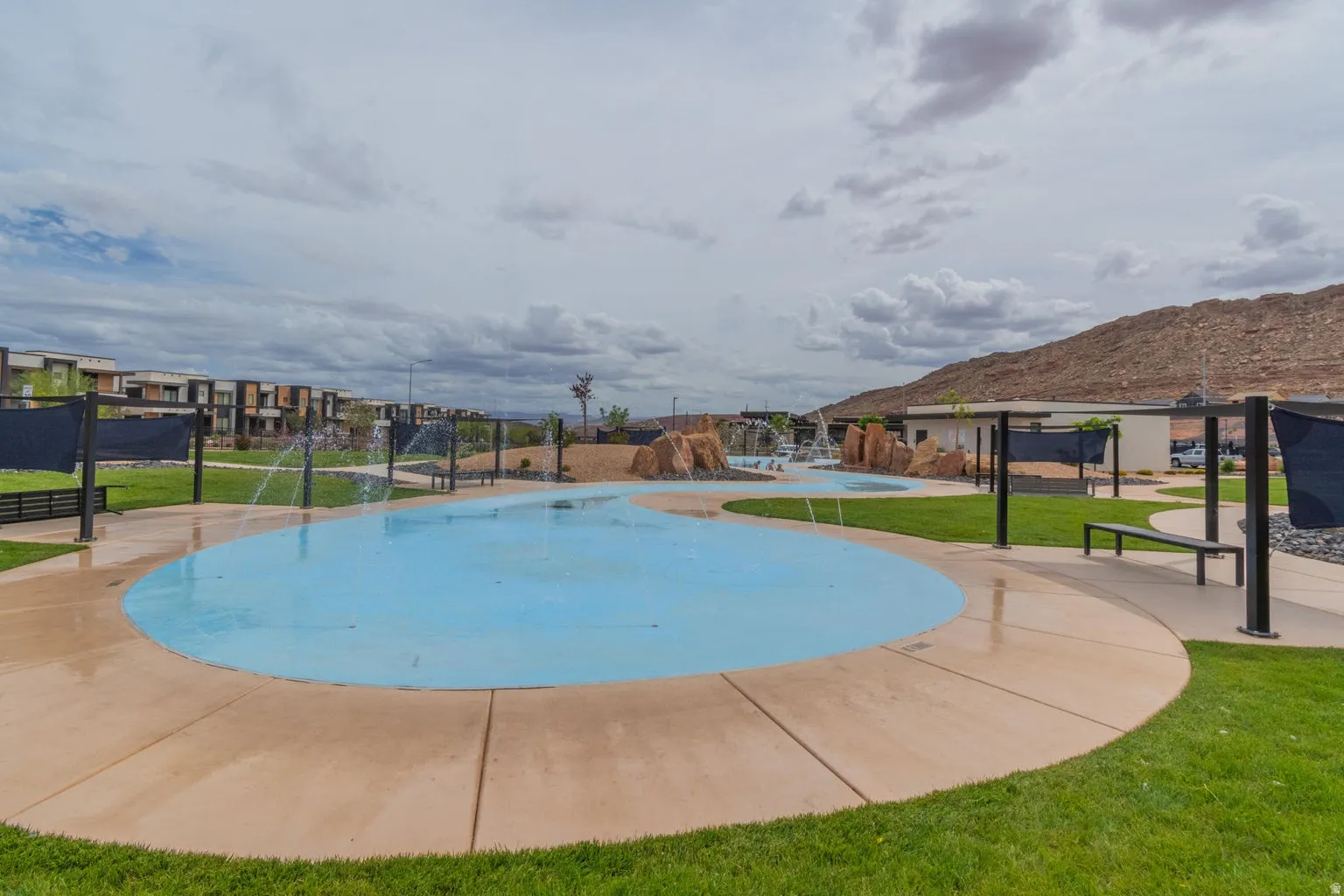 Water feature with integrated fountains, surrounded by concrete paving and manicured lawns