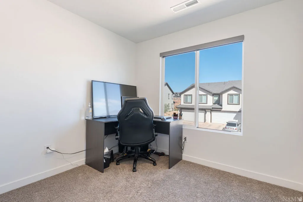 Bright room with an expansive window, neutral wall paint, and gray carpet flooring