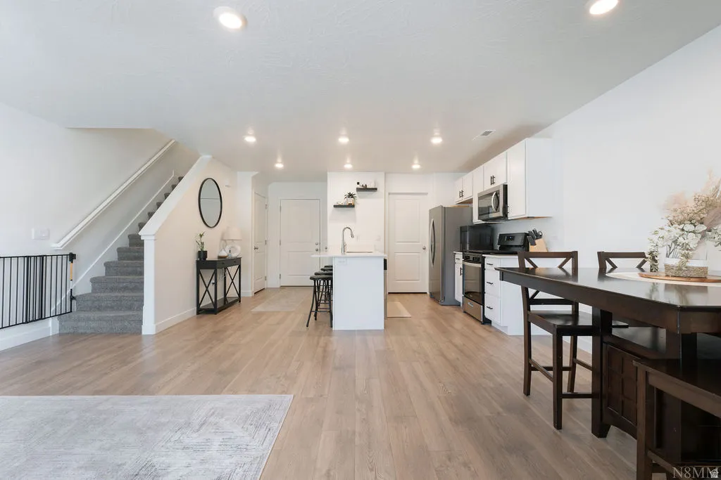 Open-concept main living area with wood-finish flooring, recessed lighting, and a neutral color palette