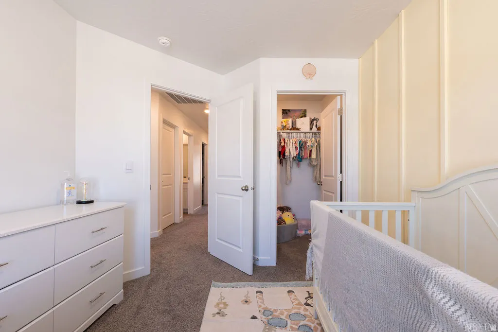 Carpeted bedroom with a built-in closet, a board and batten accent wall, and a hallway entry