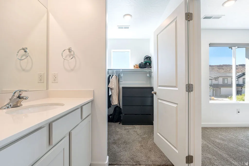 Bathroom vanity with a rectangular undermount sink, chrome faucet, and light-colored countertop