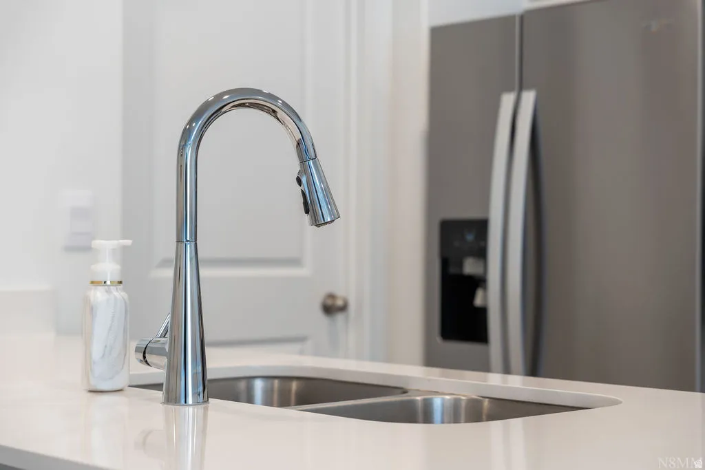 Kitchen features include a stainless steel pull-down faucet, undermount double-basin sink, and a light-toned countertop