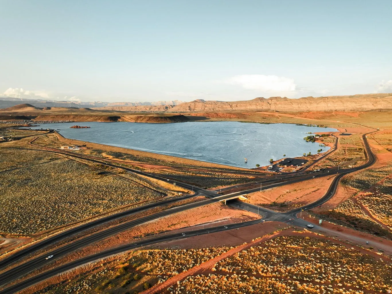 Expansive body of water bordered by undeveloped land and a network of paved roads