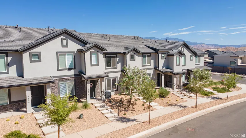 Multi-level townhome featuring a stucco exterior with stone accents and dark trim