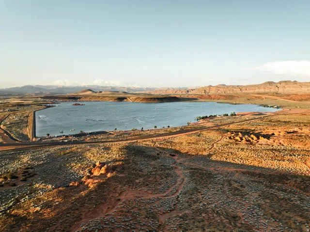 Expansive body of water with surrounding arid landscape featuring rolling hills and distant mountains