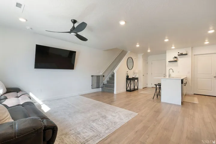 Open-concept living area with wood-finish flooring, a modern ceiling fan, and recessed lighting