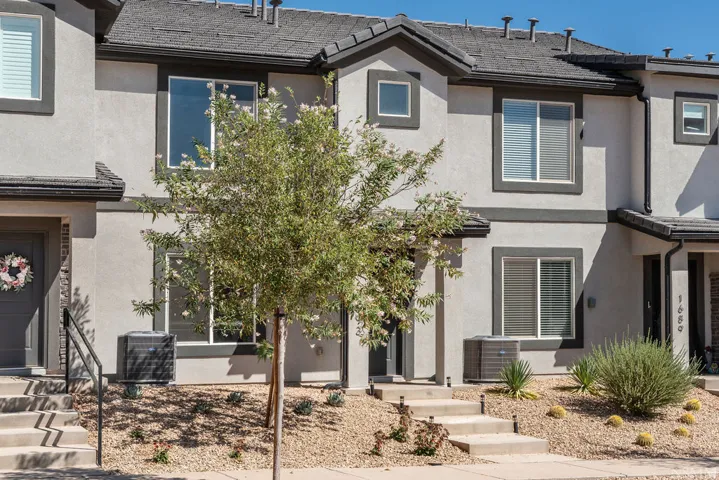 Contemporary townhome exterior featuring light gray stucco siding with dark gray trim accents