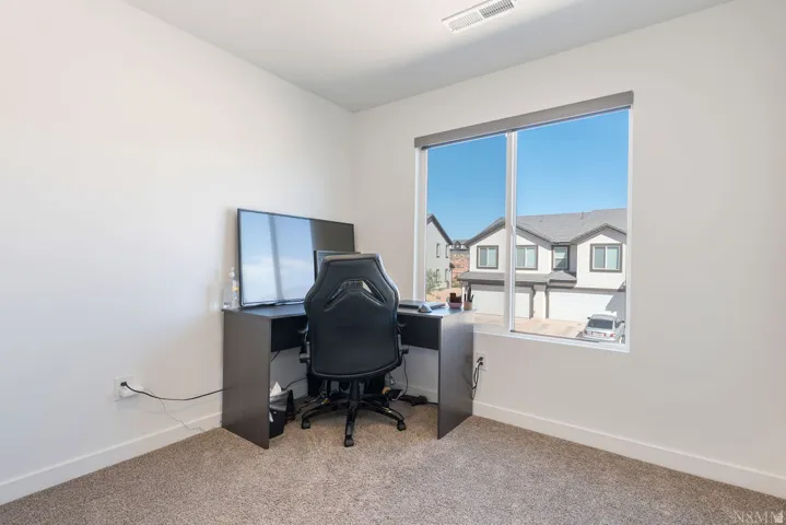 Bright room with an expansive window, neutral wall paint, and gray carpet flooring