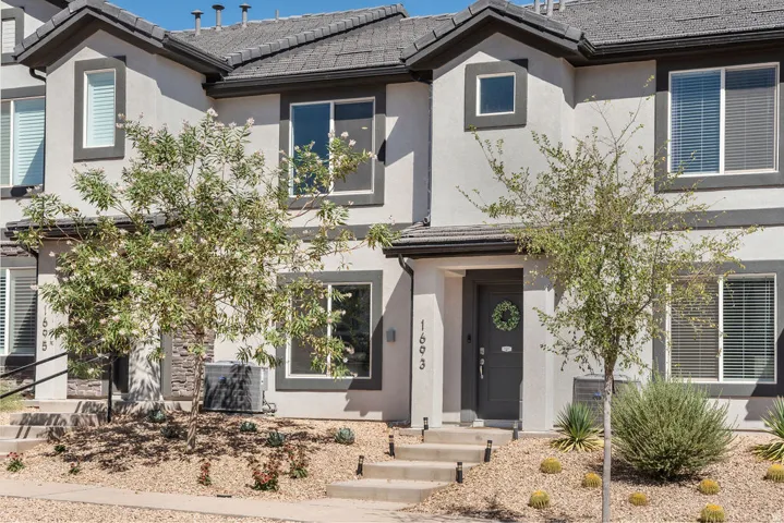 Contemporary townhome exterior featuring light stucco siding and dark trim