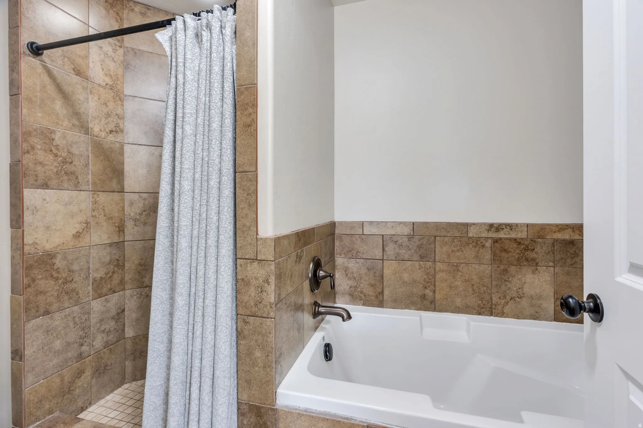 Bathroom featuring a tiled shower stall with a mosaic tile floor, an integrated bathtub, and bronze-finish fixtures