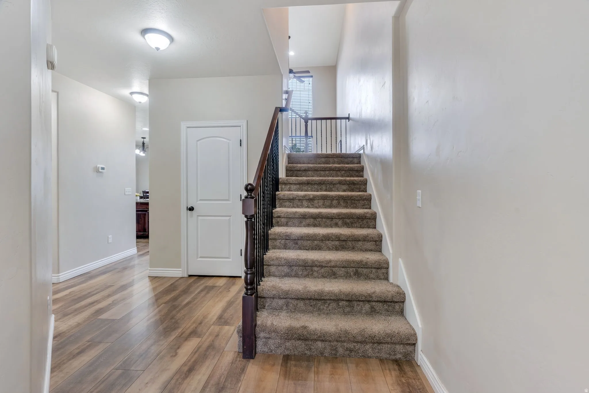 Carpeted staircase with dark wood newel post and wrought iron balusters