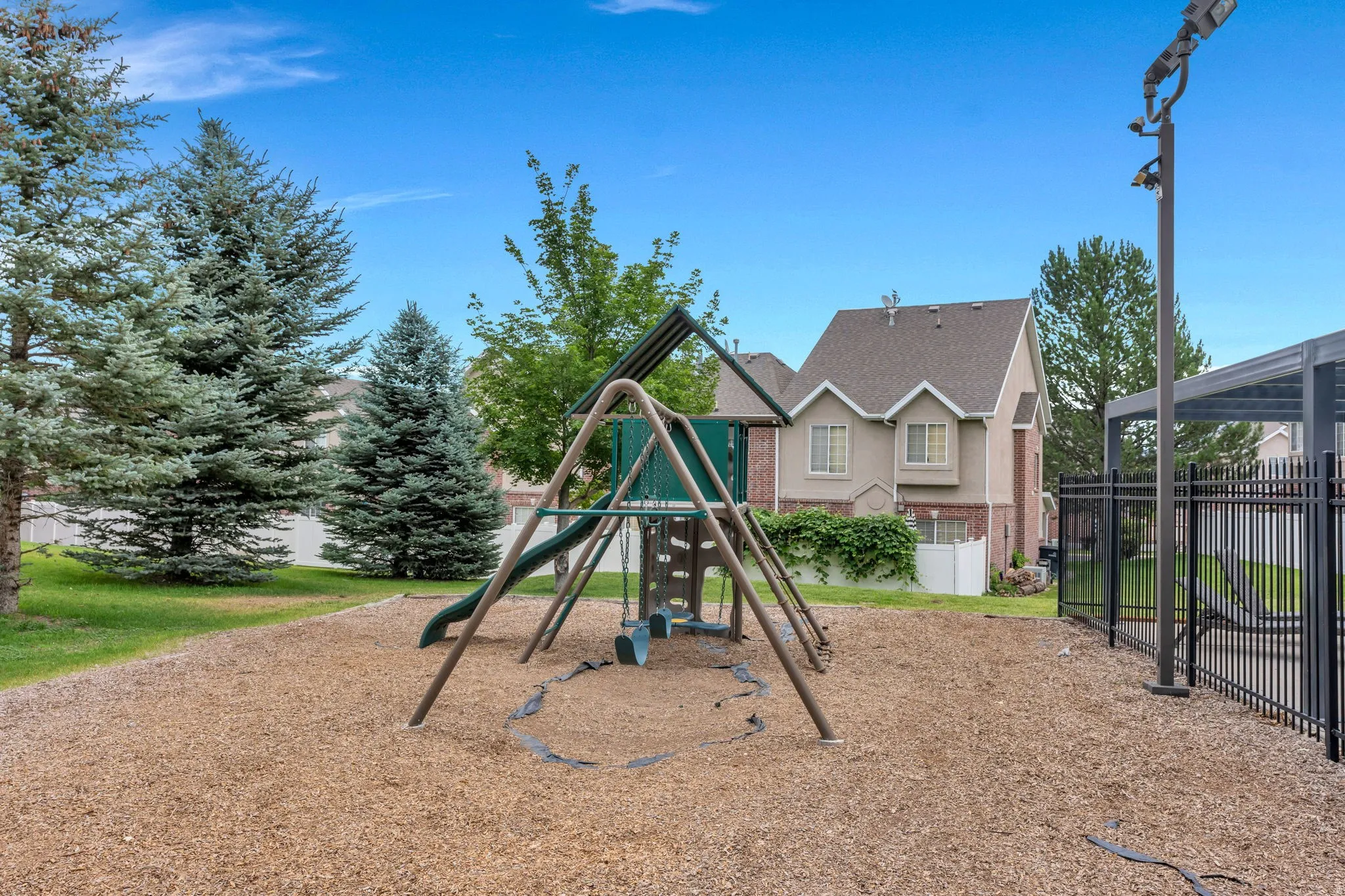 Outdoor playground featuring a swing set, slide, and wood chip surfacing