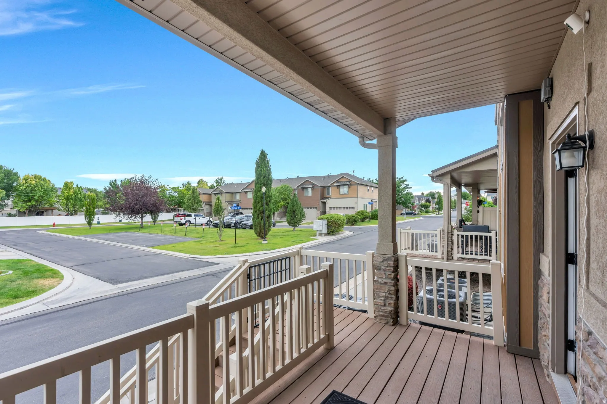 Covered outdoor deck with composite decking, white railing, and stone-wrapped pillars