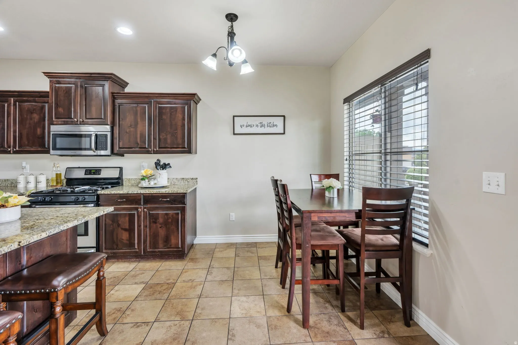 Kitchen featuring dark wood cabinetry, light-toned countertops, stainless steel appliances, and a gas range
