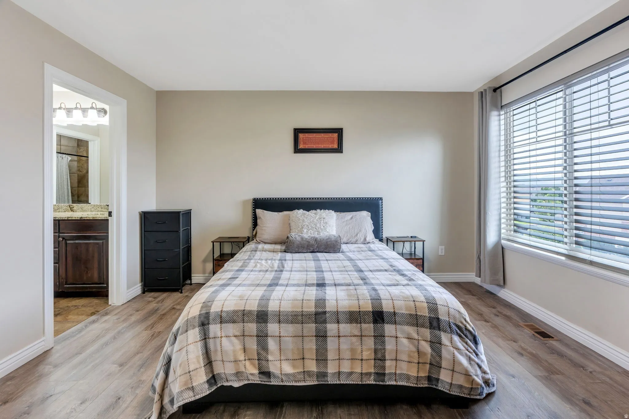 Spacious room featuring wood-finish flooring and a large window with blinds