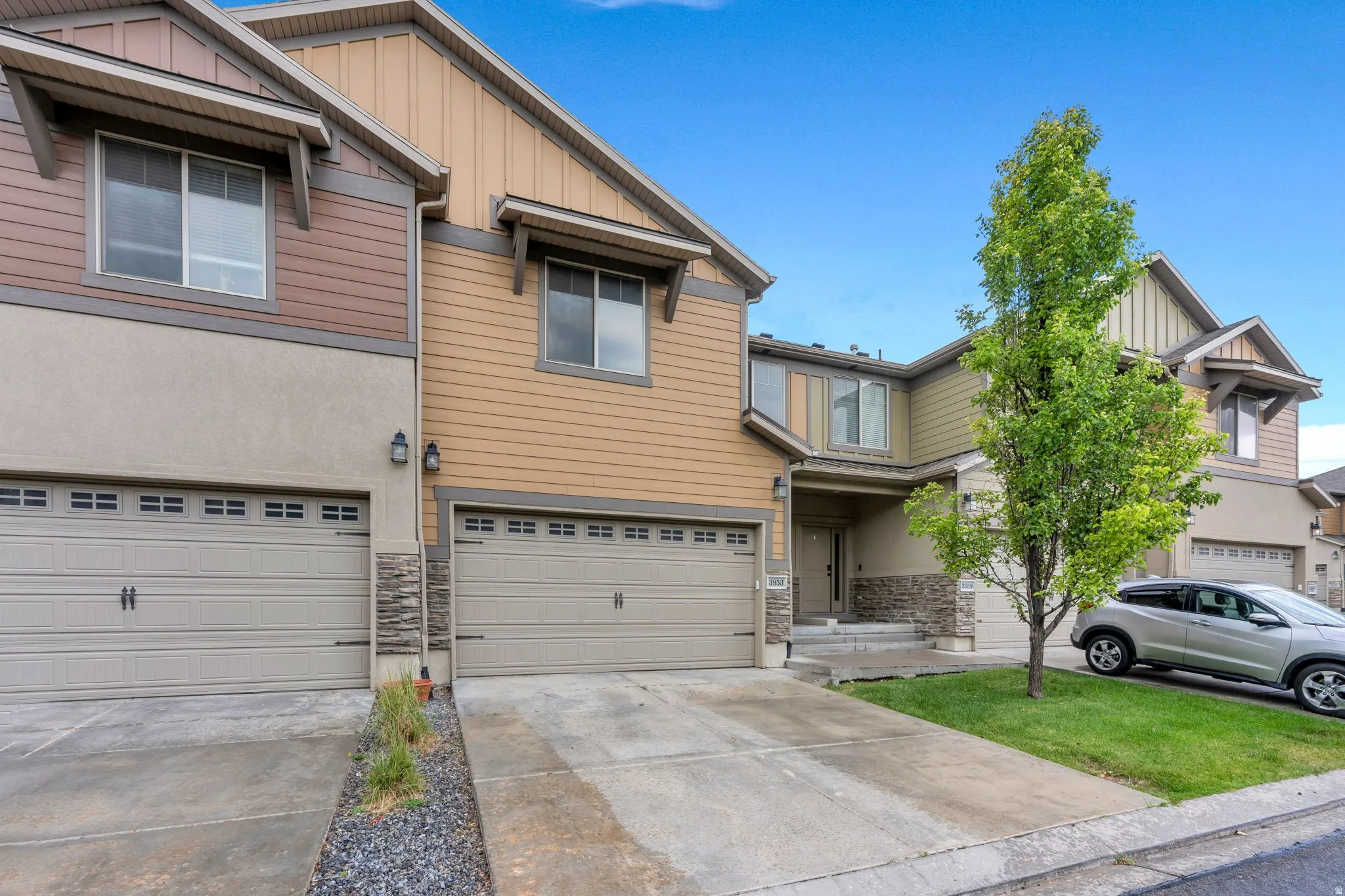 Multi-story townhome with neutral-toned siding and stone veneer accents
