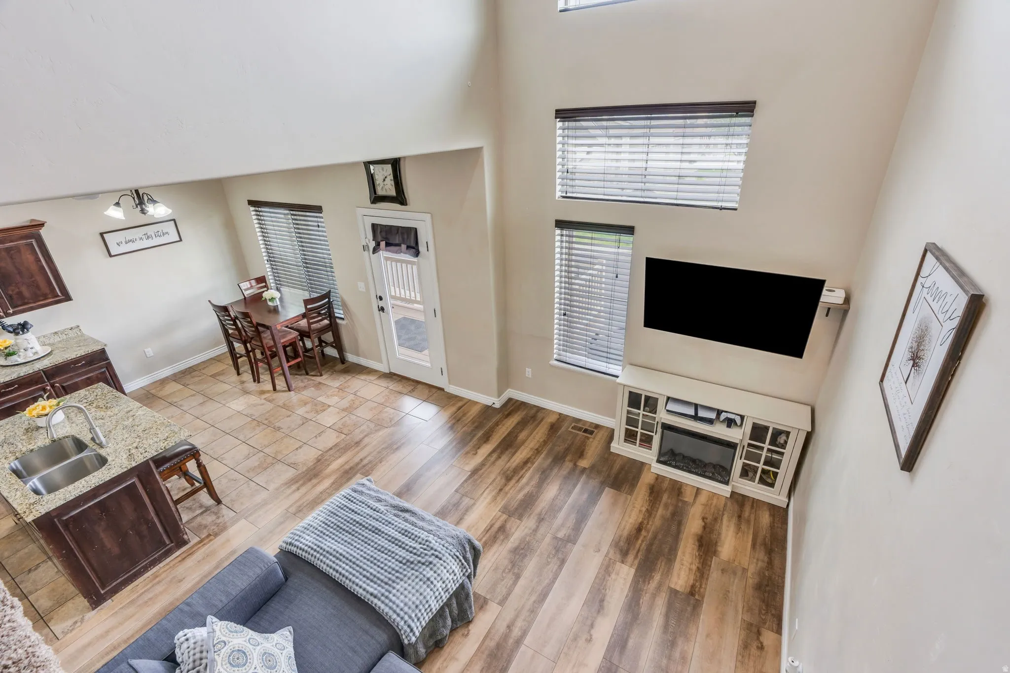 Open-concept living space featuring wood-finish flooring, a contemporary fireplace console, and multiple windows