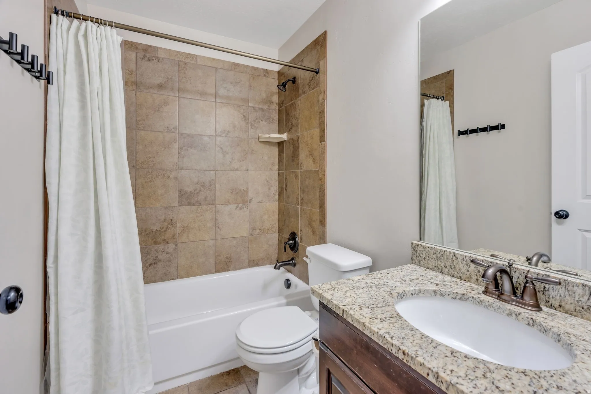 Bathroom featuring a dark wood vanity with a light-toned granite countertop, an undermount sink, and oil-rubbed bronze fixtures
