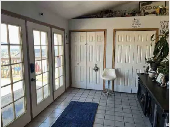Interior space featuring triple French doors with grid-patterned glass, light-toned tile flooring, and white bifold closet doors