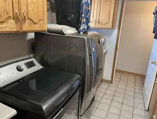 Utility area with light wood-finish cabinetry, neutral tiled flooring, and a countertop surface