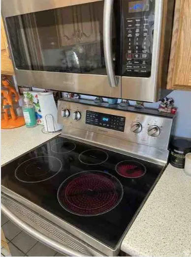 Stainless steel over-the-range microwave and electric range with a black ceramic glass cooktop