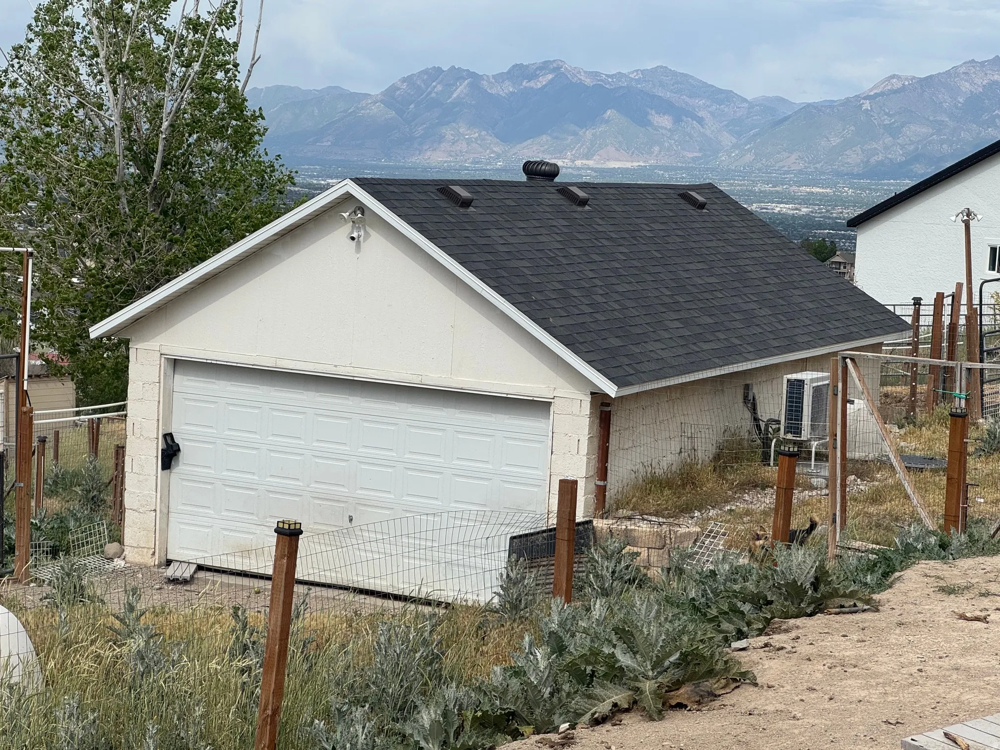 Detached garage structure featuring a white panel garage door and dark asphalt shingle roof