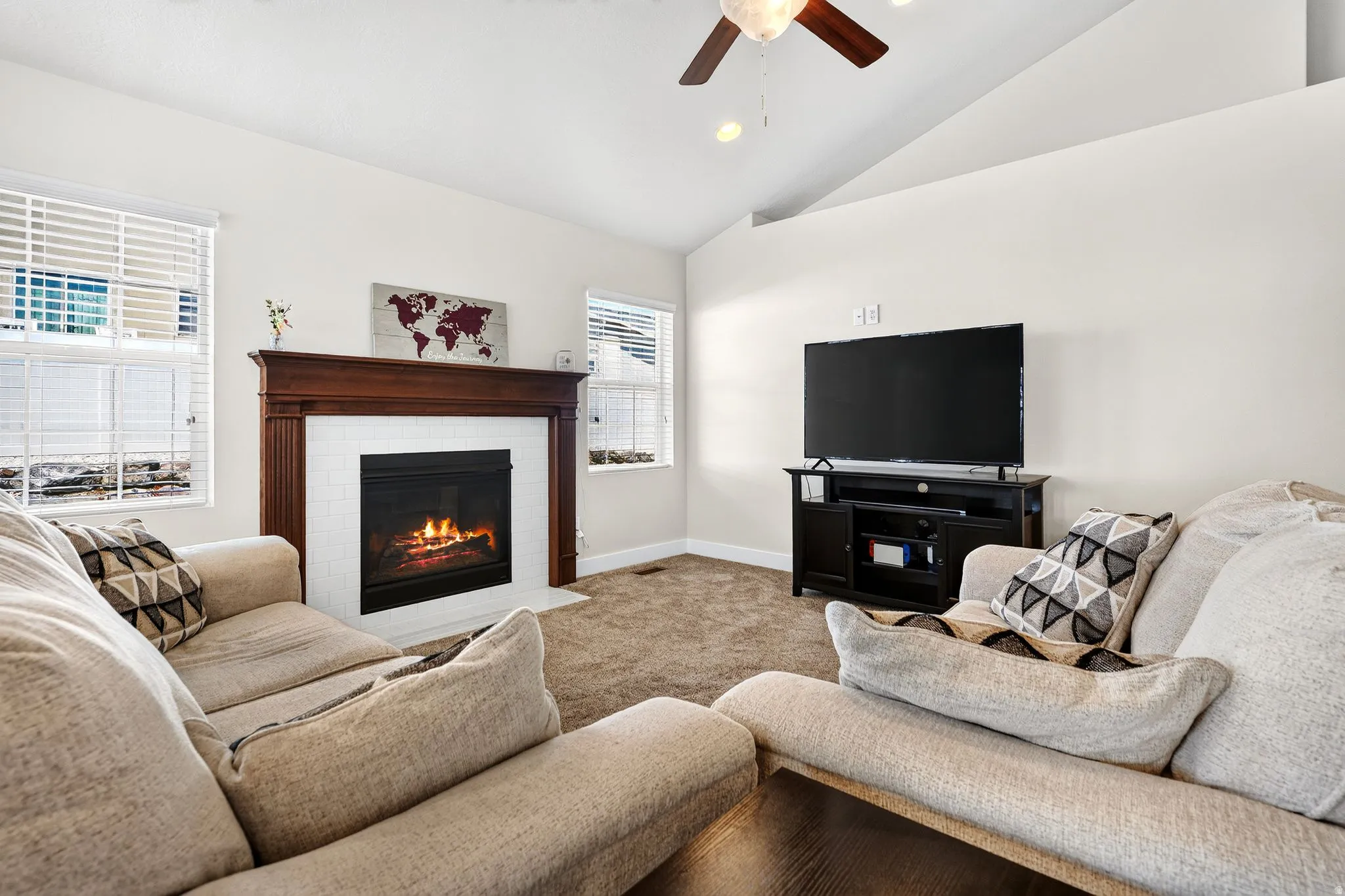 Living room featuring a gas fireplace with a wood mantel, white tile surround, and an integrated ceiling fan