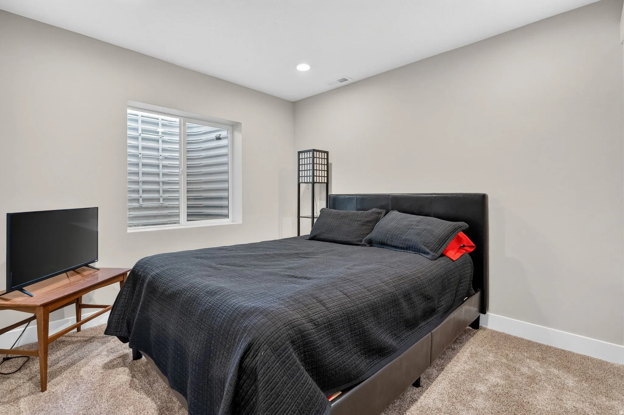 Carpeted room featuring a white-framed egress window