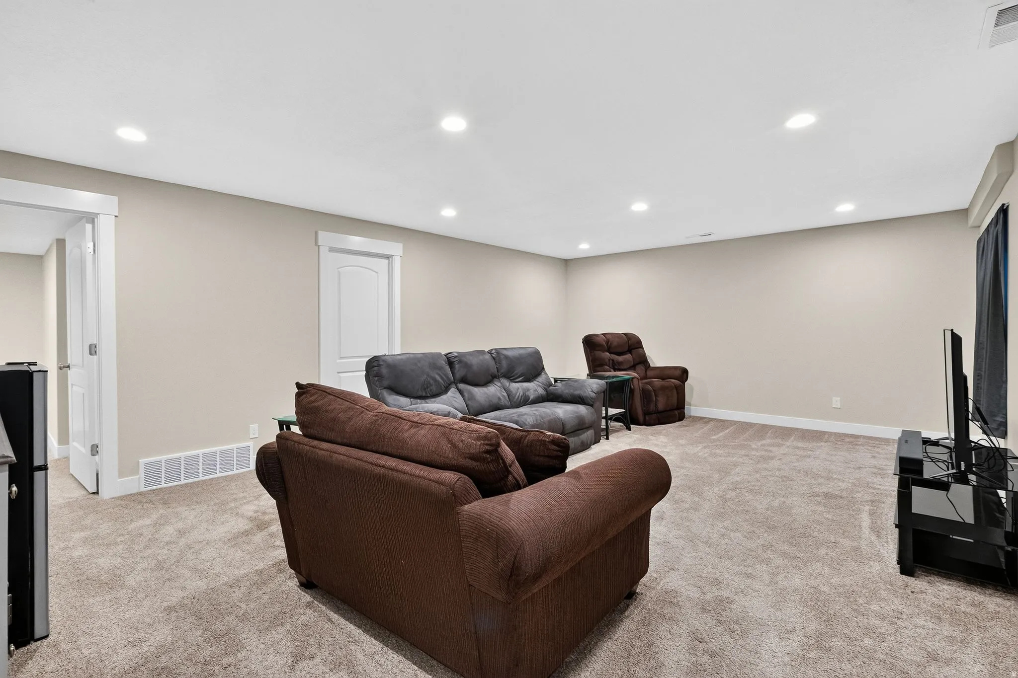 Spacious room featuring neutral-toned walls, recessed lighting, and plush carpet flooring