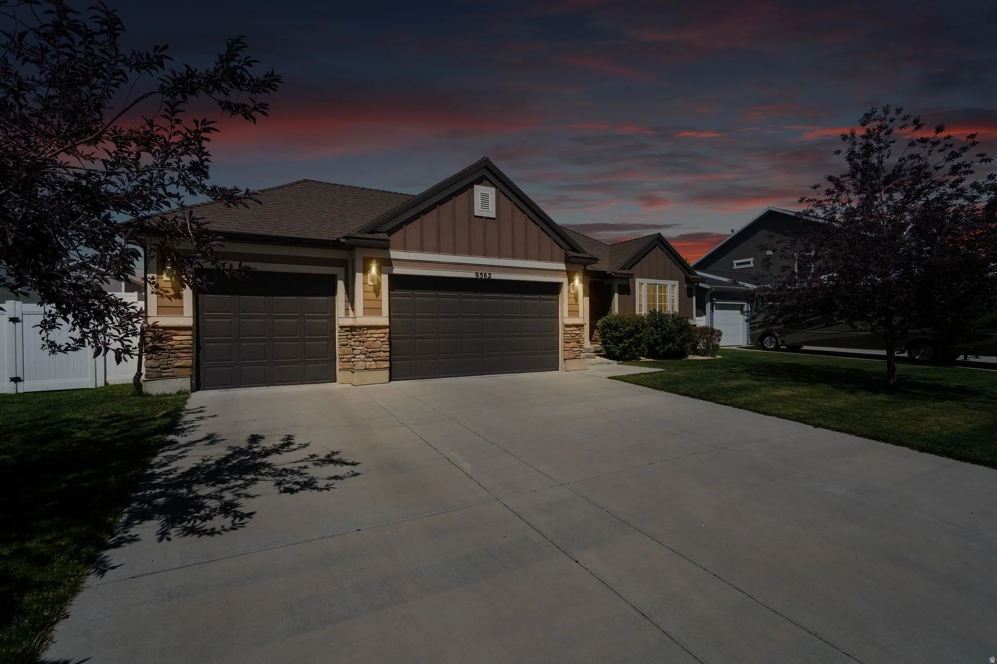 Ranch-style exterior with a two-car garage, stone accents, horizontal siding, and a concrete driveway