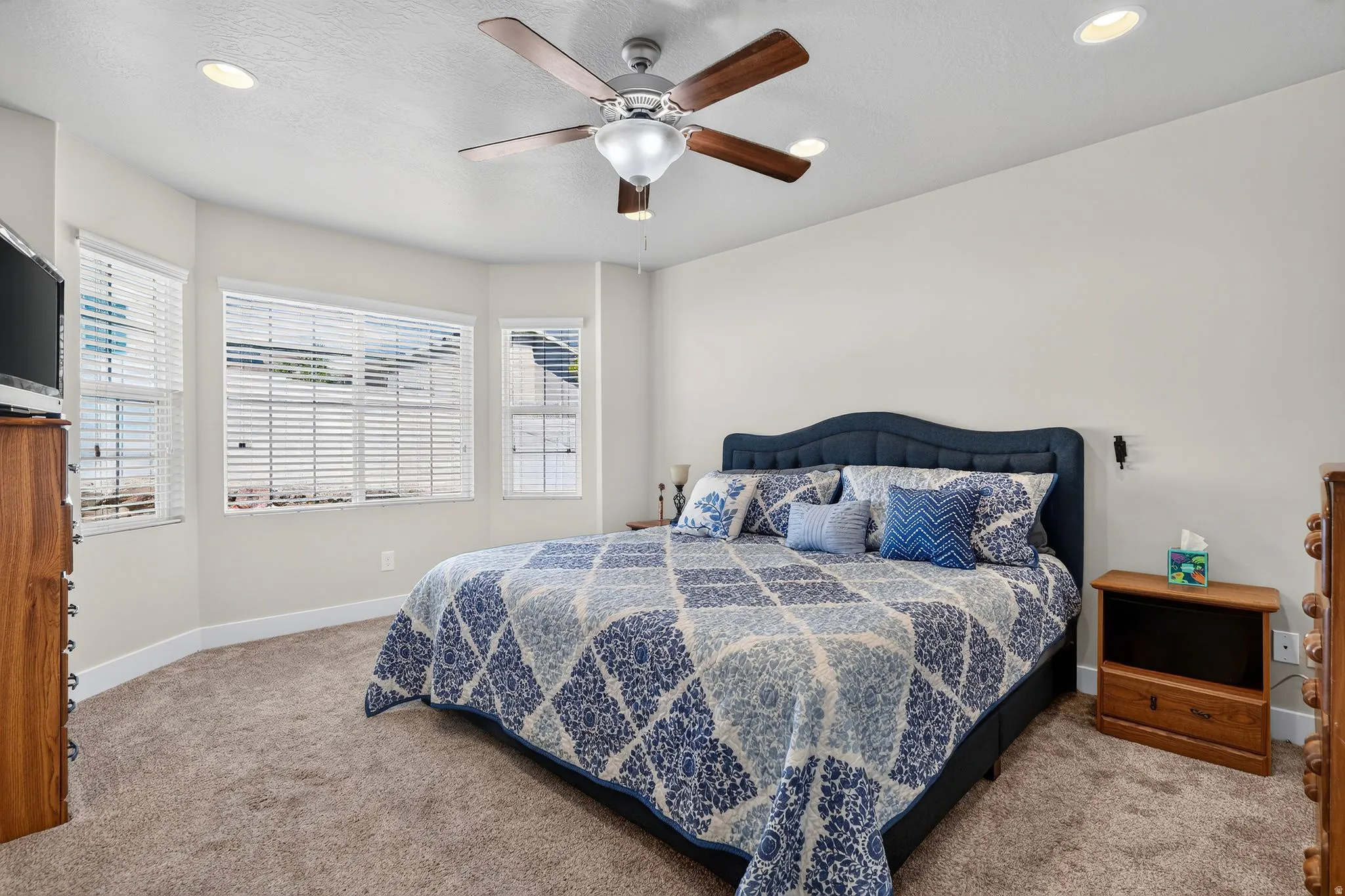 Carpeted bedroom featuring a bay window, ceiling fan, and recessed lighting