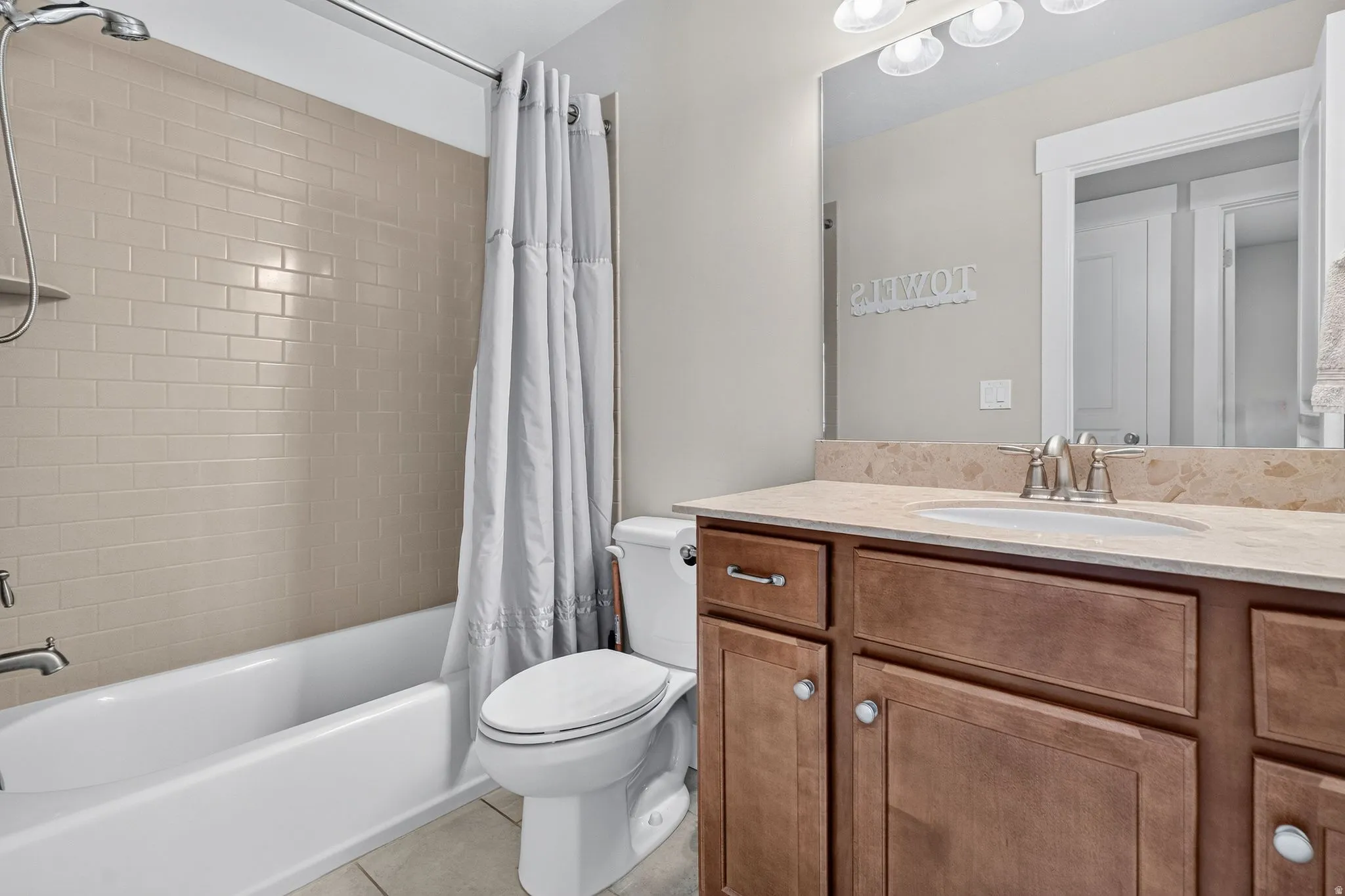 Bathroom featuring a vanity with wood-finish cabinetry, a light-toned countertop, and an undermount sink