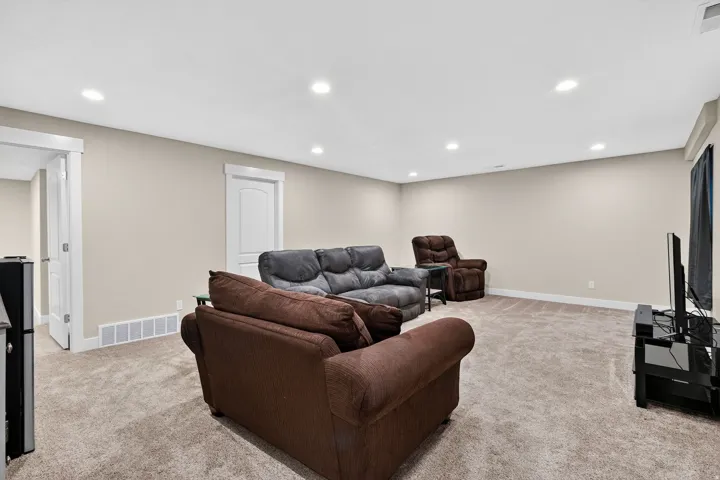 Spacious room featuring neutral-toned walls, recessed lighting, and plush carpet flooring