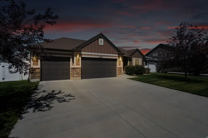 Ranch-style exterior with a two-car garage, stone accents, horizontal siding, and a concrete driveway