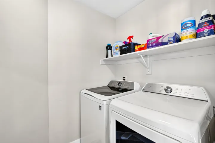 Dedicated laundry area featuring white walls and a white wall-mounted shelf