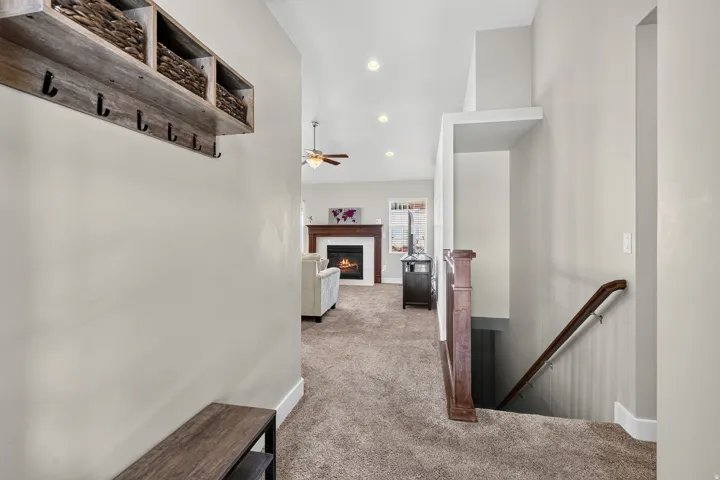 Entryway with built-in storage bench and overhead shelving, leading to a living area featuring a fireplace with a wood mantel