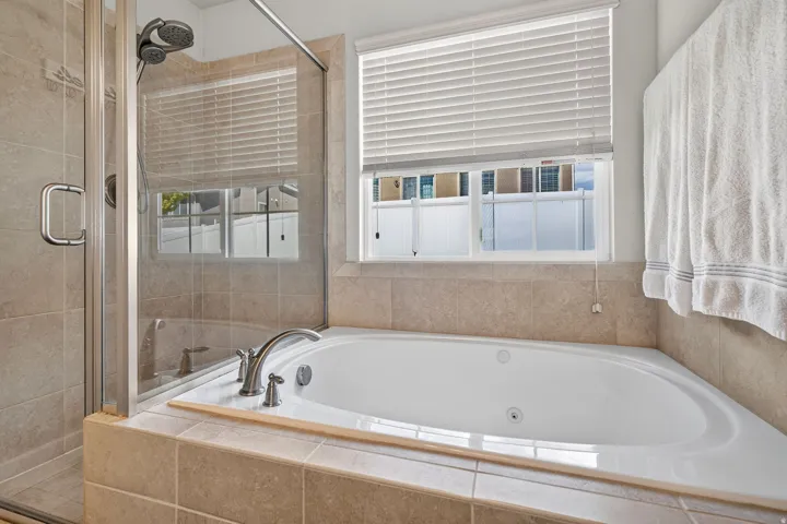 Soaking tub with tile surround, brushed nickel fixtures, and a dual-head shower with glass enclosure
