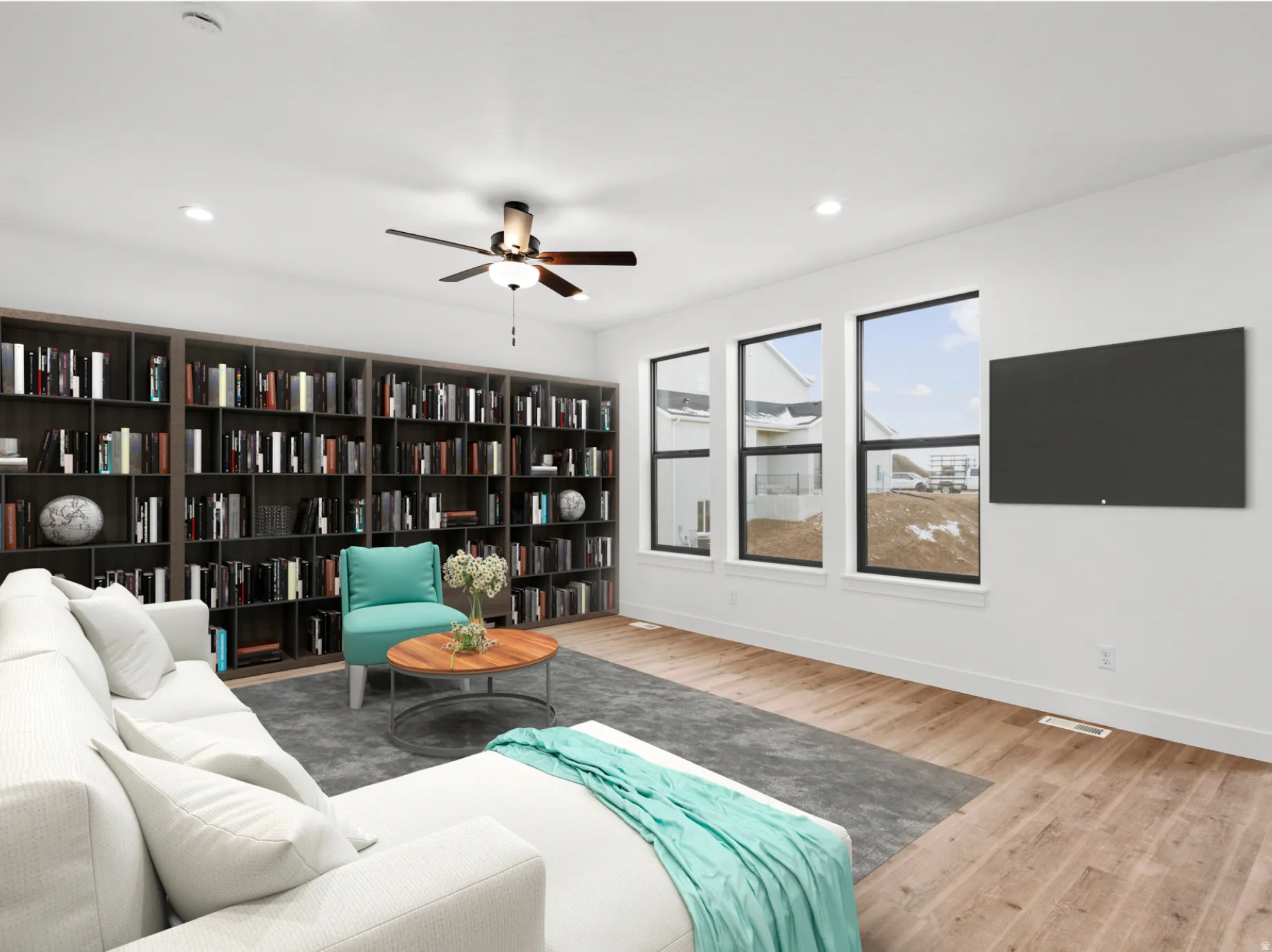 Spacious living area featuring extensive built-in shelving, recessed lighting, and wood-finish flooring