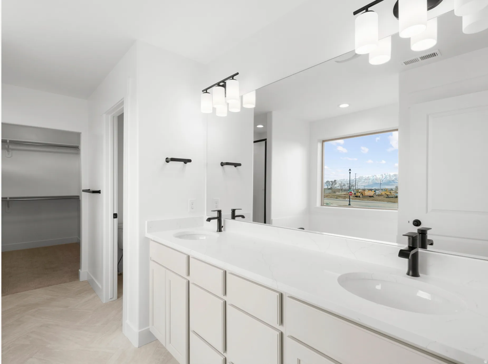 Dual vanity with white cabinetry, integrated sinks, white countertops, and black fixtures