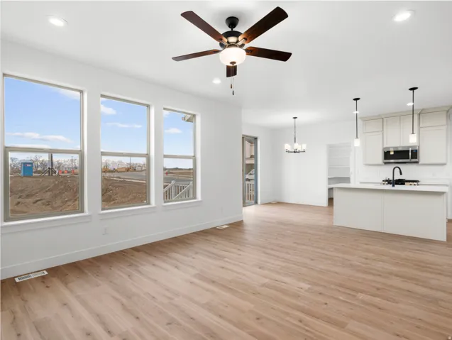 Open-concept living space with wood-finish flooring, recessed lighting, and a ceiling fan