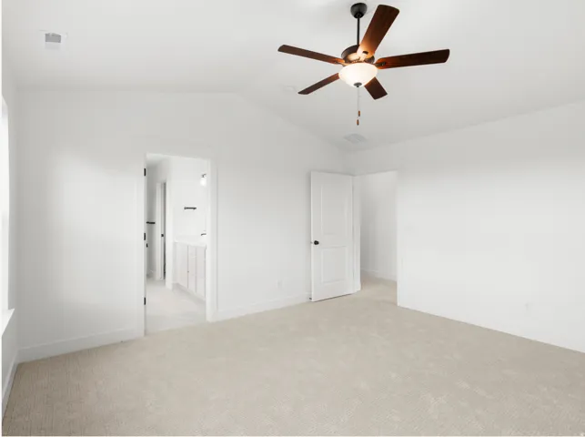 Vaulted ceiling room featuring light-toned carpeting, a ceiling fan with dark wood-finish blades, and a white paneled door