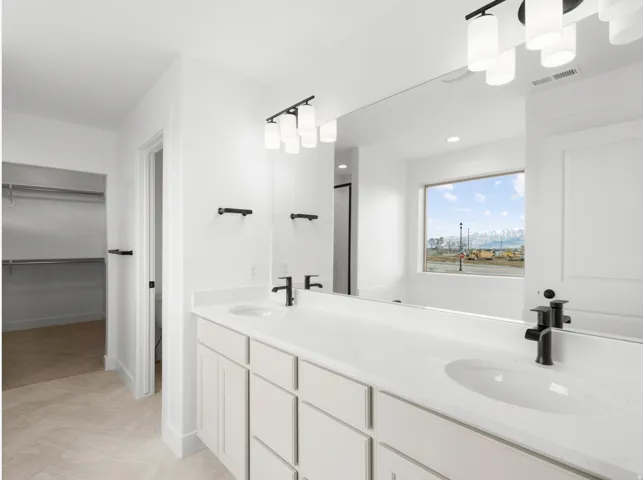 Dual vanity with white cabinetry, integrated sinks, white countertops, and black fixtures
