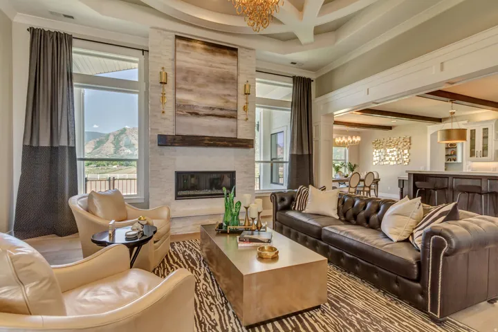 Living area featuring a coffered ceiling, large windows, and a stone-clad fireplace with a wood mantel