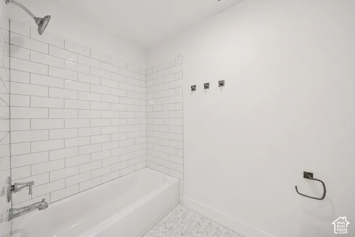 Bathroom featuring a white subway-tiled shower surround, a full bathtub with chrome fixtures, and a herringbone-patterned floor tile